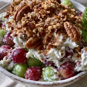 Ultra close-up high-angle photo of luscious Creamy Grape Salad in a white ceramic bowl with red and green grapes.
