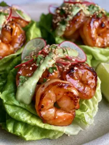 Macro view of charred jumbo shrimp with a glistening chili-lime glaze in butter lettuce cups.