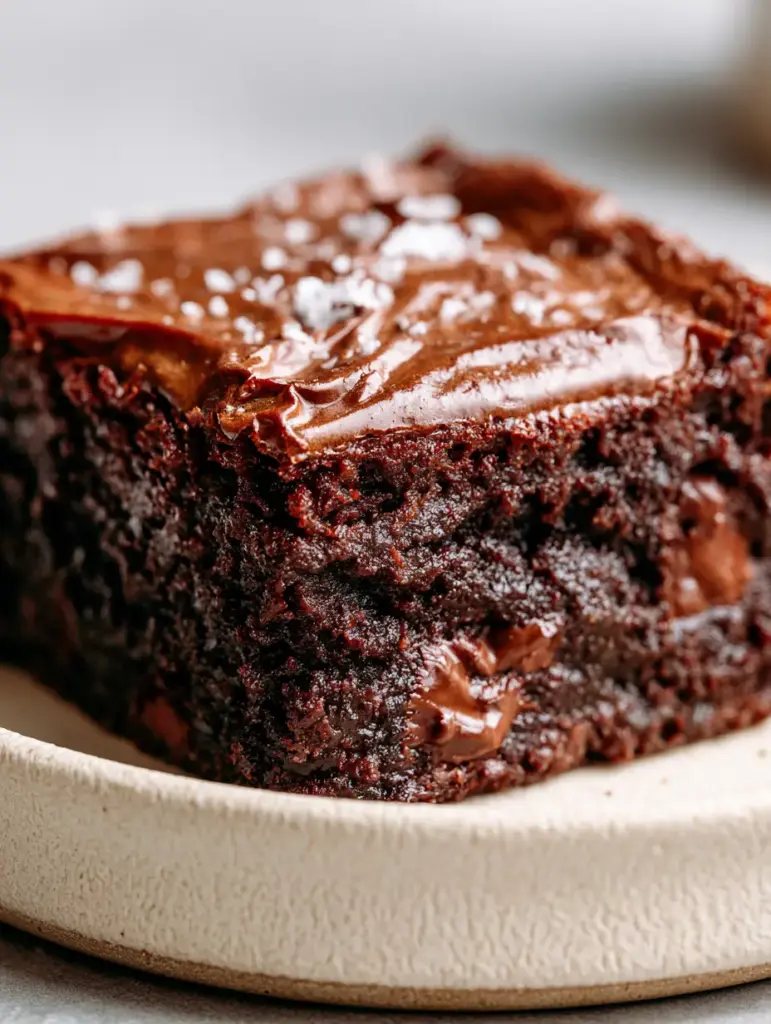 A close-up of a brownie slice revealing melted semi-sweet chocolate chunks and flaky sea salt.