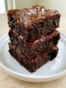 Eye-level shot of sharp-edged Fudgy Brownie Squares with semi-melted dark chocolate pockets and a shiny crust.